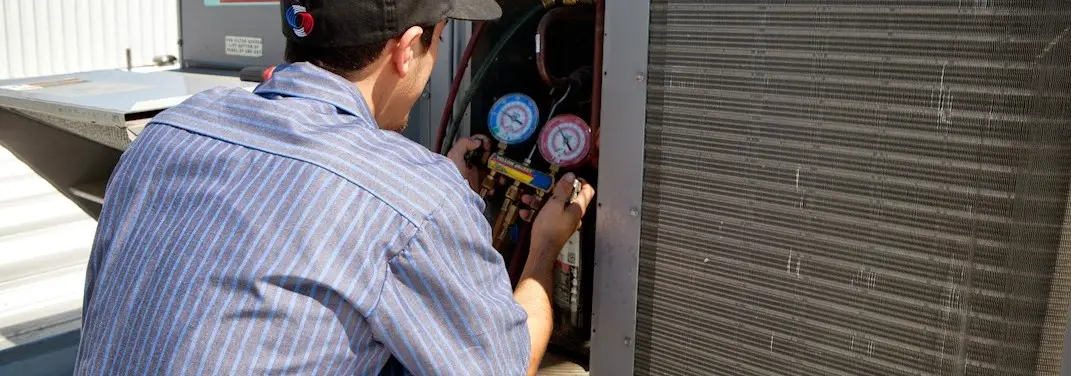 HVAC technician servicing a condenser unit in College