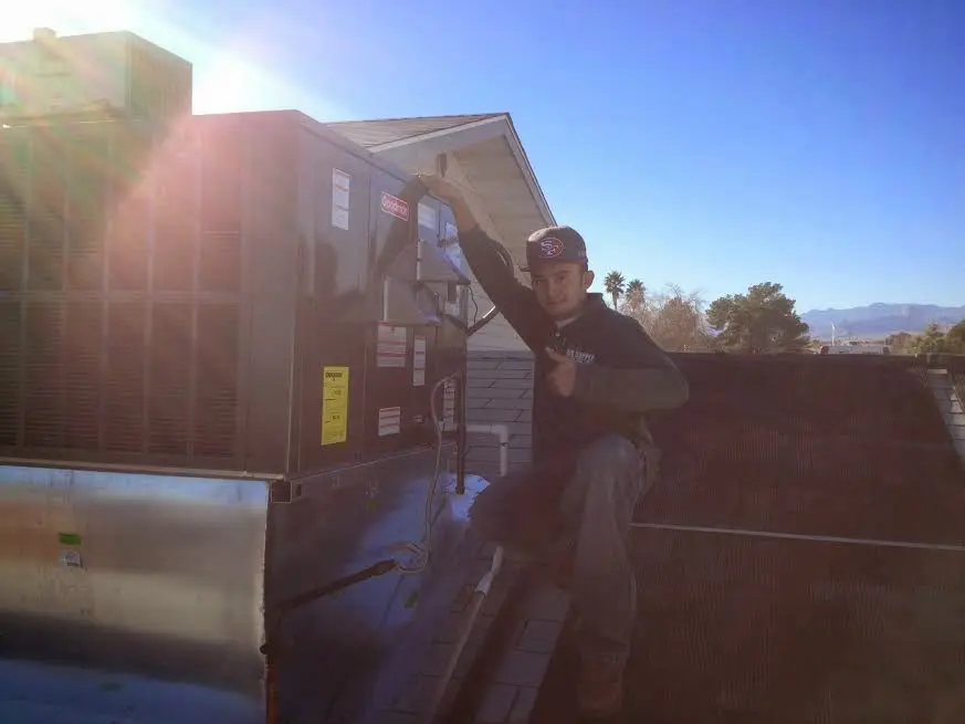 HVAC technician performing Heat Pump Repair on a rooftop unit in College